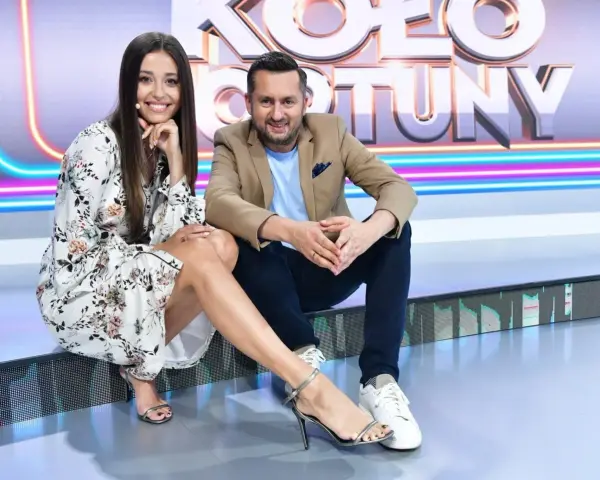Uśmiechnięta prowadząca i Rafał Brzozowski, kto prowadzi Koło Fortuny, siedzą na scenie.