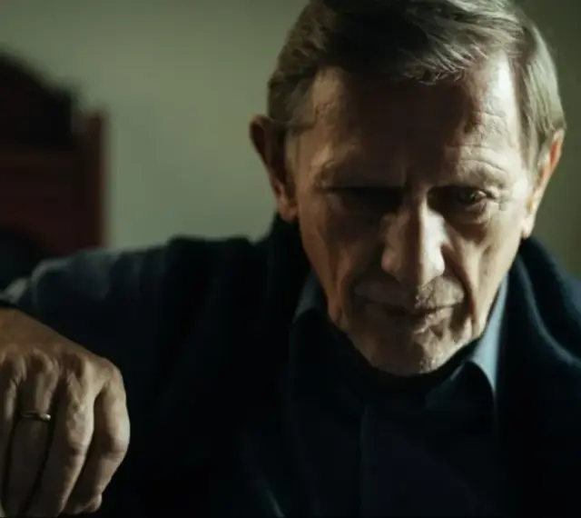 Jan Englert w filmach, zamyślony, z dłonią opartą o laskę.