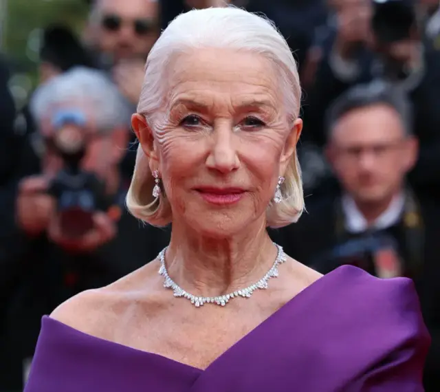 Helen Mirren w fioletowej sukni, olśniewająca na czerwonym dywanie. Jej bogata kariera obejmuje niezliczone filmy, seriale i programy.