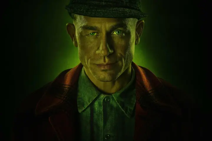 Mężczyzna z zielonymi oczami i czapką na głowie, w tle zielona poświata. Zapowiada mroczne seriale kryminalne Netflix.