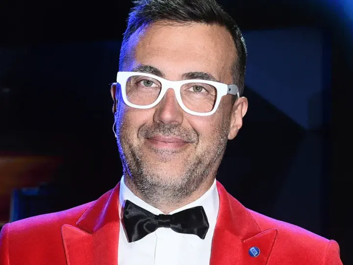 DJ z "Jaka to melodia?" w czerwonej marynarce i białych okularach, gotowy do zabawy.
