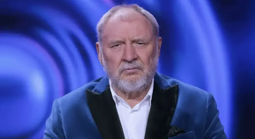 Andrzej Grabowski żyje i wygląda na zmęczonego, siedząc w niebieskiej marynarce na tle niebieskich świateł.