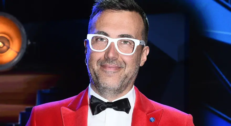 DJ z "Jaka to melodia?" w czerwonej marynarce i białych okularach, gotowy do zabawy.