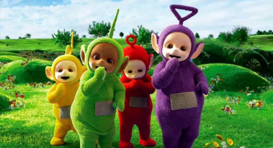 Teletubisie imiona: Tinky Winky, Dipsy, Laa-Laa i Po stoją na zielonej łące pełnej kwiatów.