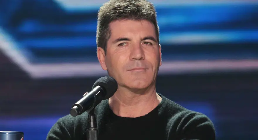 Simon Cowell, znany z surowych ocen, siedzi przy mikrofonie. Plotki o tym, że Simon Cowell nie żyje, są fałszywe.