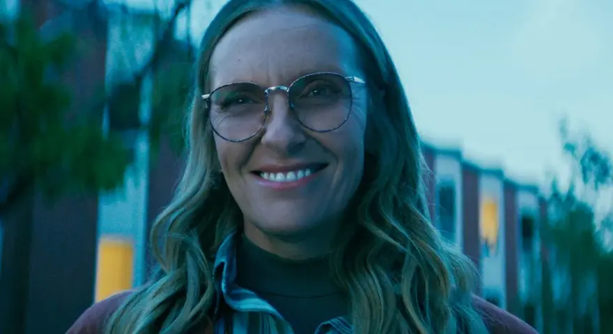 Uśmiechnięta Toni Collette w okularach, znana z wielu filmów i seriali, wygląda na zadowoloną.