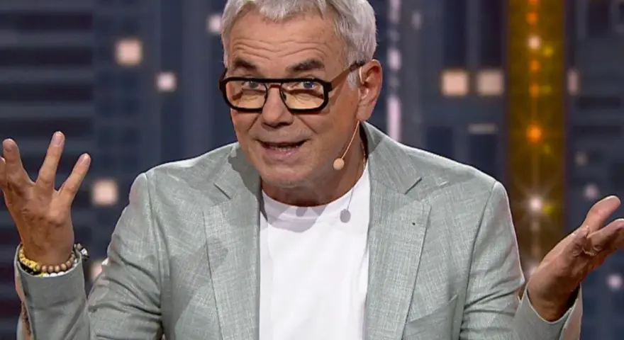 Kto prowadził "Jaka to melodia"? To Hubert Urbański, znany prezenter, w jasnej marynarce i okularach, z gestykulacją.
