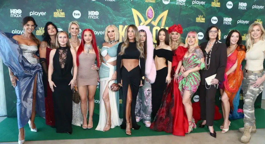 Królowe przetrwania 3 na premierze. Grupa kobiet w barwnych kreacjach pozuje na zielonym tle z logotypami wydarzenia.