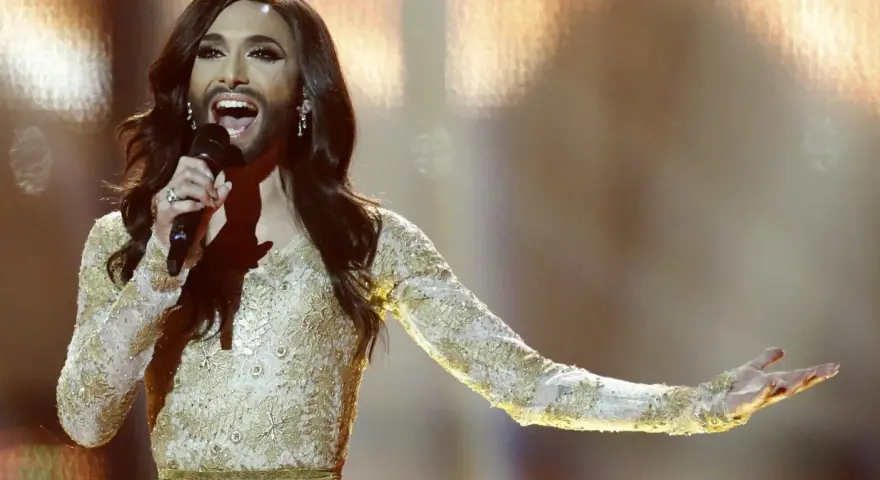 Conchita Wurst, zwyciężczyni Eurowizji, w złotej sukni z cekinami śpiewa na scenie.