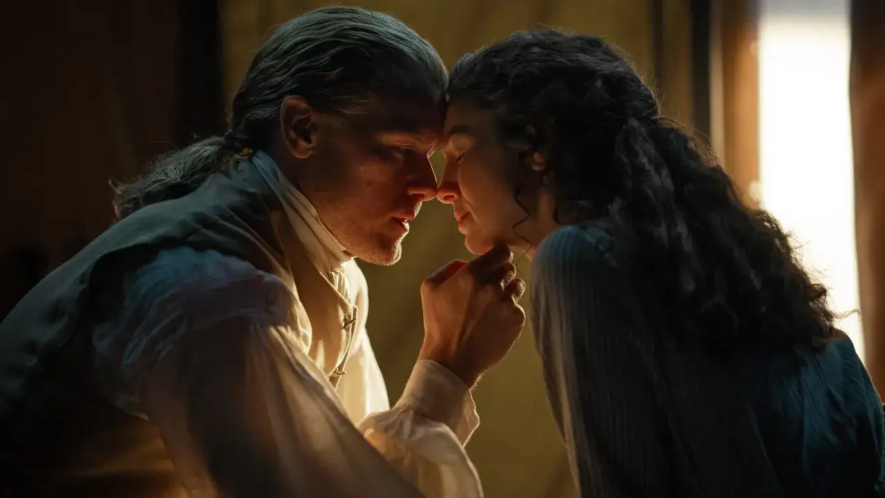 Jamie i Claire w intymnym uścisku, ich czoła się stykają. To scena z outlander sezon 8, pełna emocji i tęsknoty.