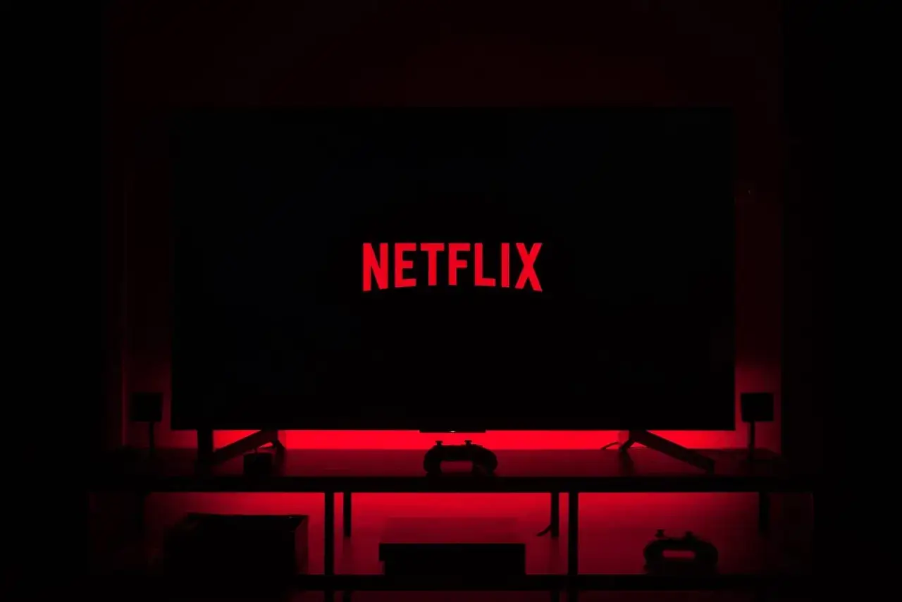 Ciemny pokój, telewizor z czerwonym logo Netflix. Czas na maraton seriali Netflix!