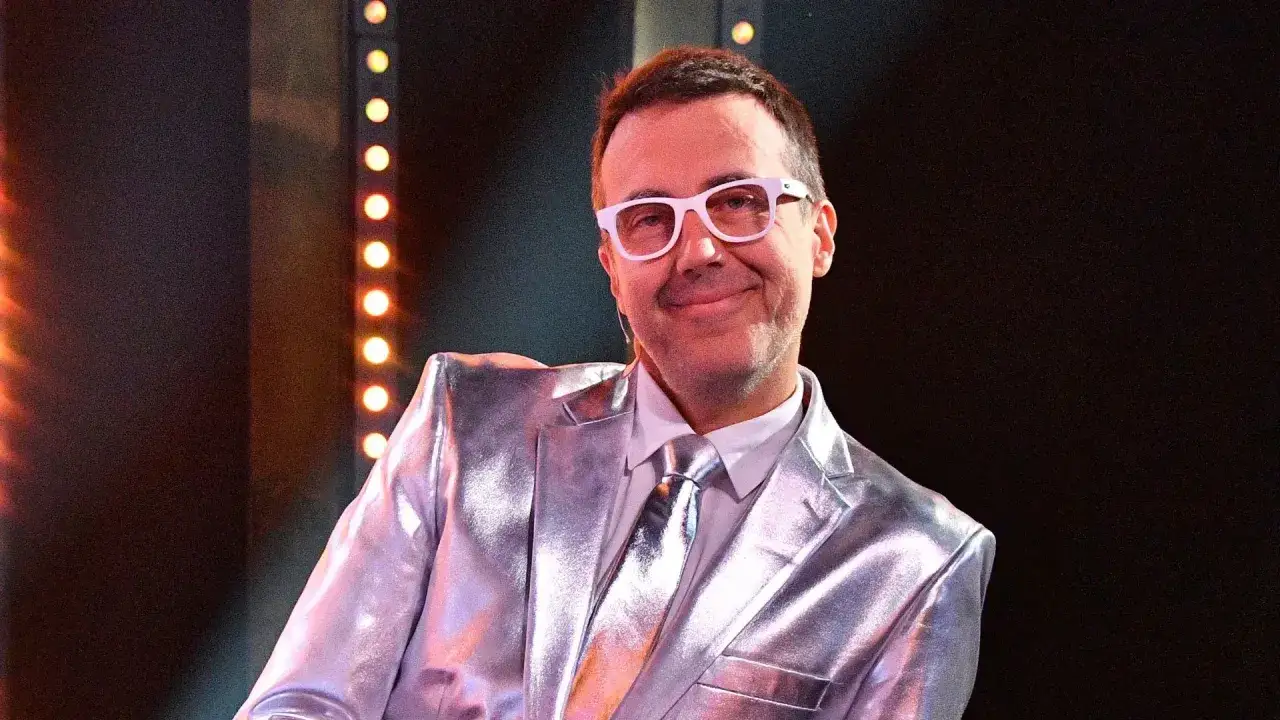 DJ w błyszczącym garniturze i białych okularach, gotowy do zabawy w