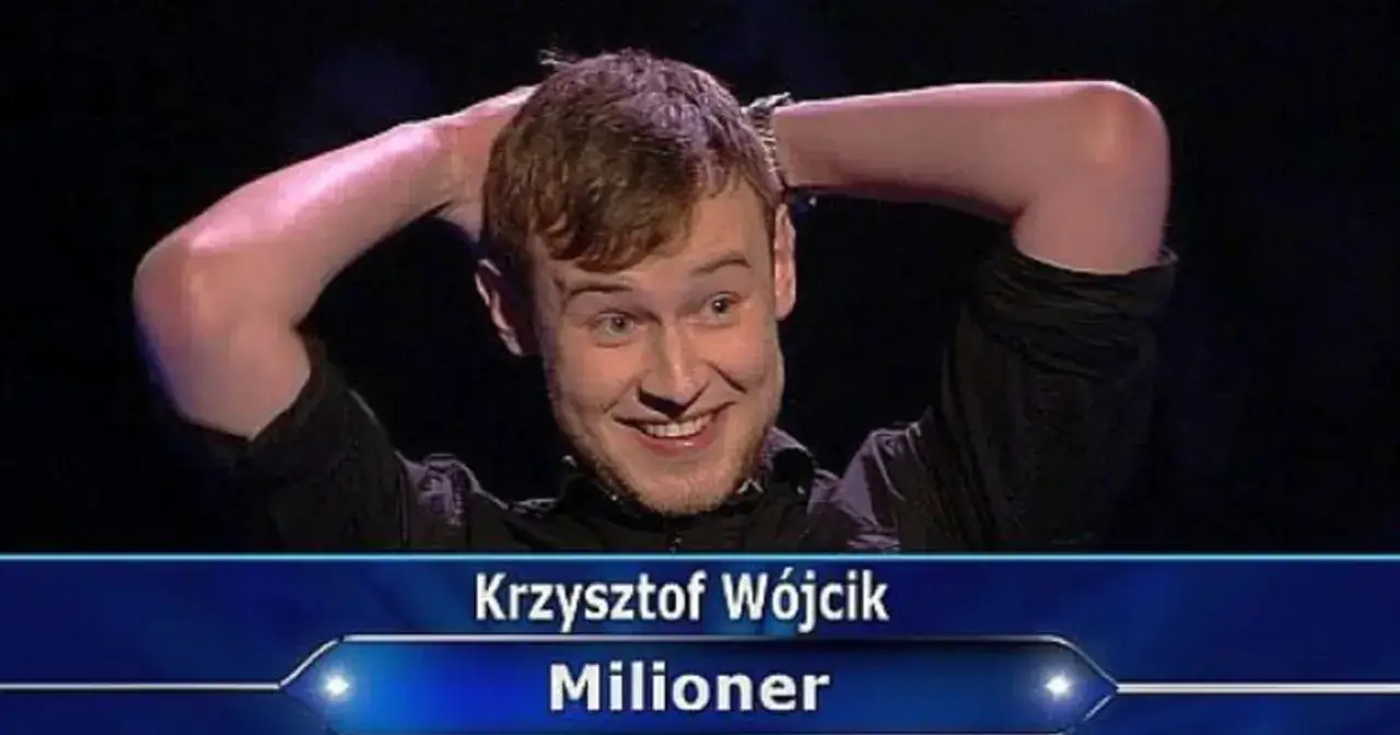 Krzysztof Wójcik, bohater odcinka Milionerów, z rękami za głową, uśmiecha się szeroko.