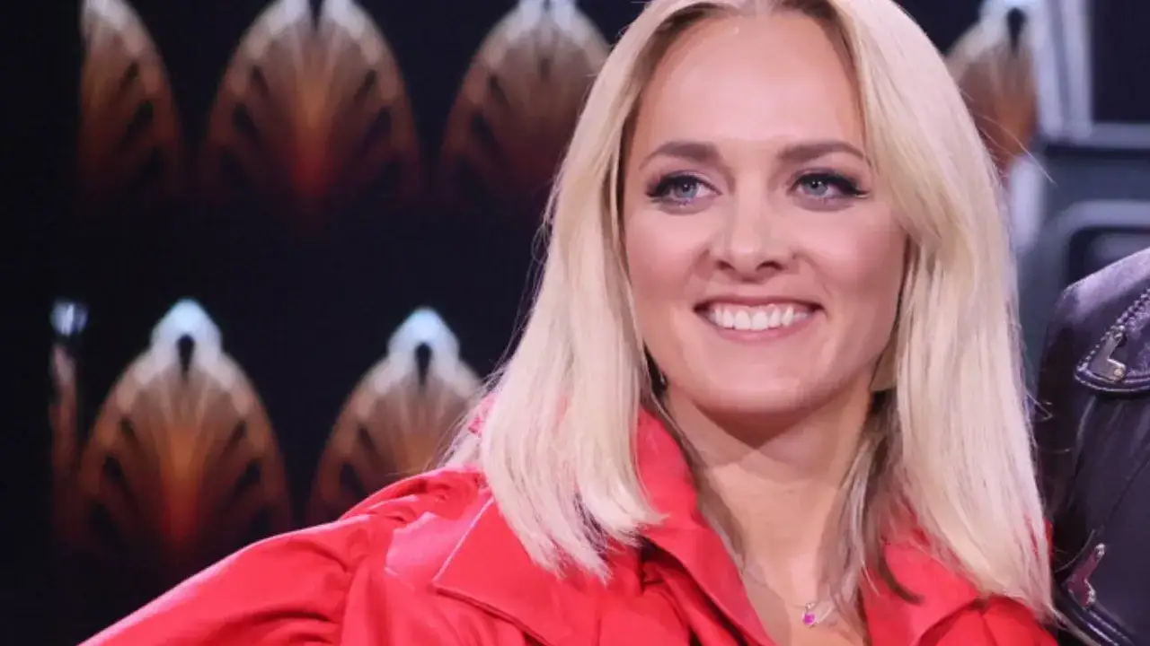 Uśmiechnięta Aleksandra Radwan w czerwonej marynarce, gotowa do zgadywania w