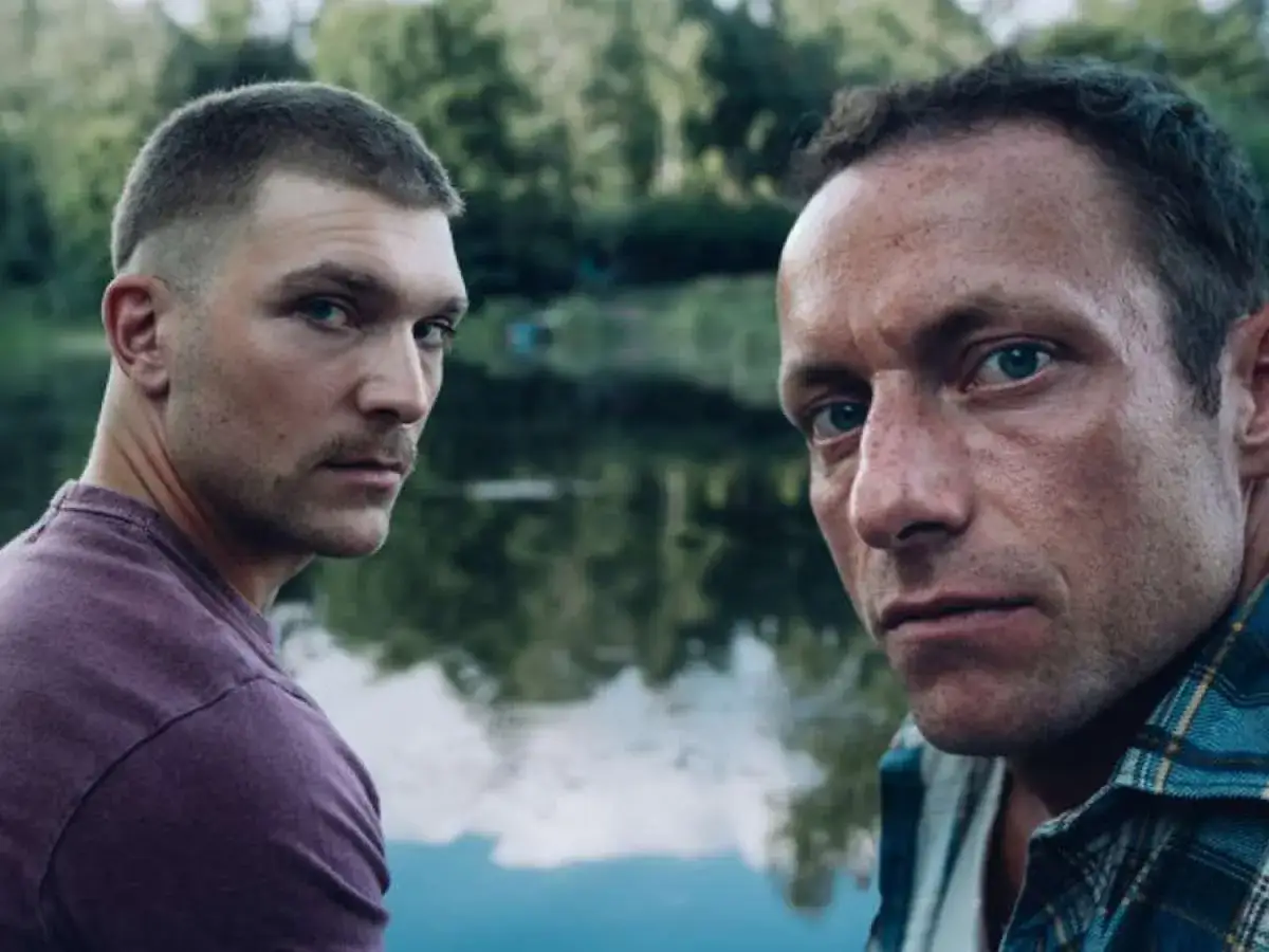 Dwóch mężczyzn patrzy w kamerę, w tle jezioro. To kadr z polskiego serialu Netflix.
