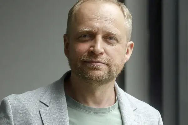 Piotr Adamczyk, znany z wielu filmów, seriali i programów, w jasnej marynarce i zielonej koszulce.